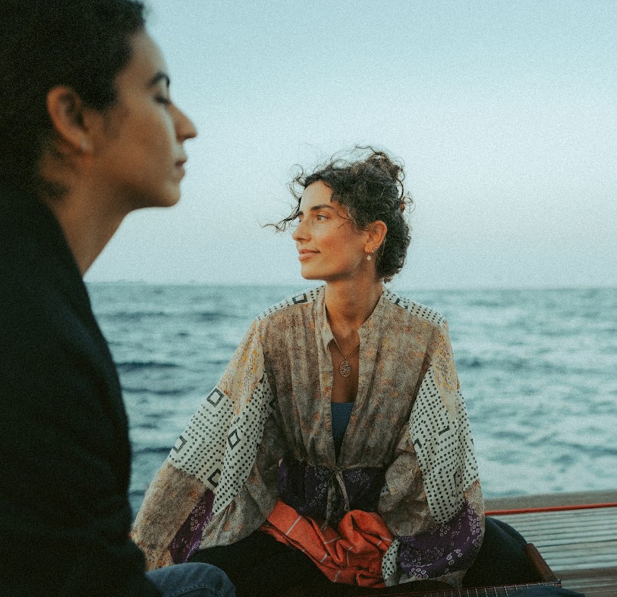 Two guests sitting on the sailboat at dusk, looking out over the Mediterranean